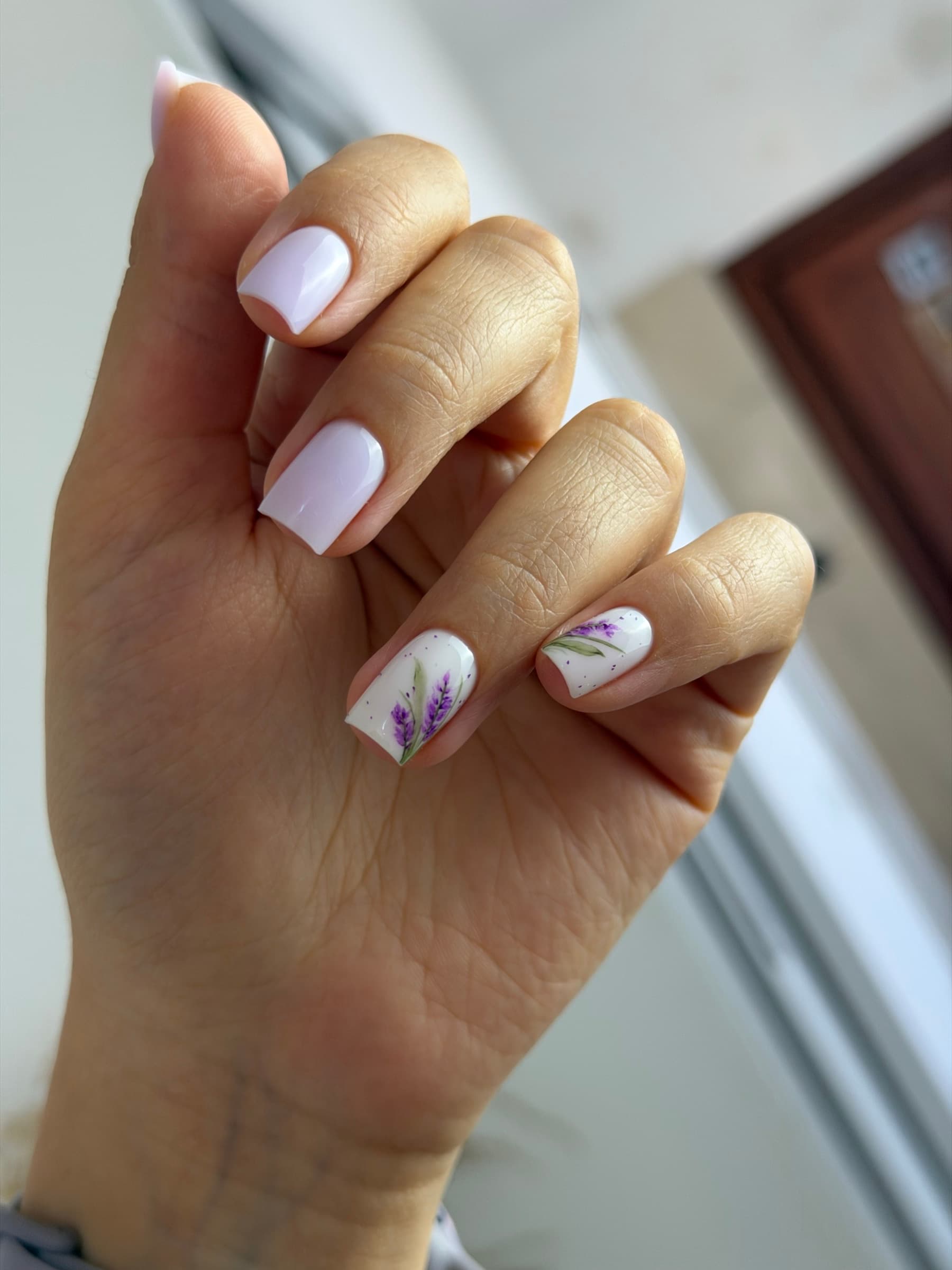 White base manicure with hand-painted lavender floral accent nails